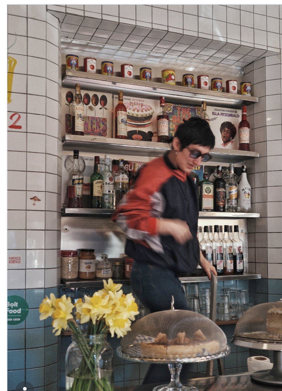 The tiled Plantastic bar with cakes under glass domes, daffodils and shelves of bottles