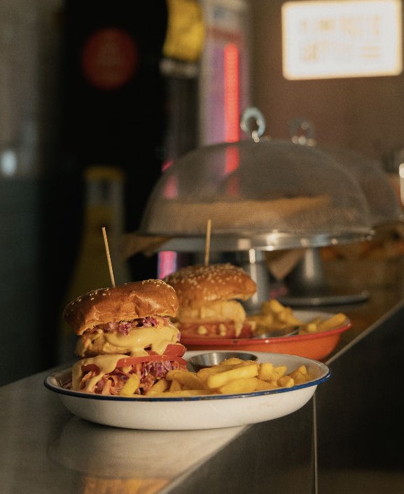 A loaded vegan cheeseburger and fries on an enamel plate