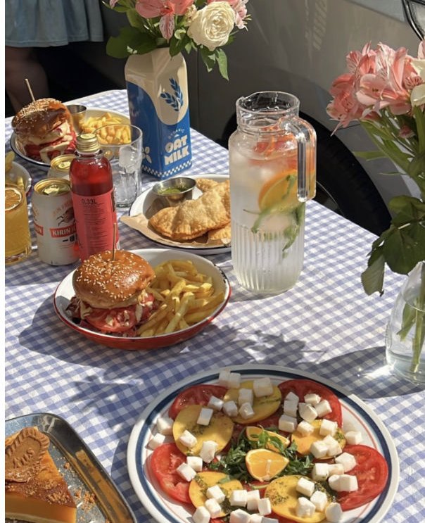 A vegan burger and tomato-feta caprese on a blue gingham cloth