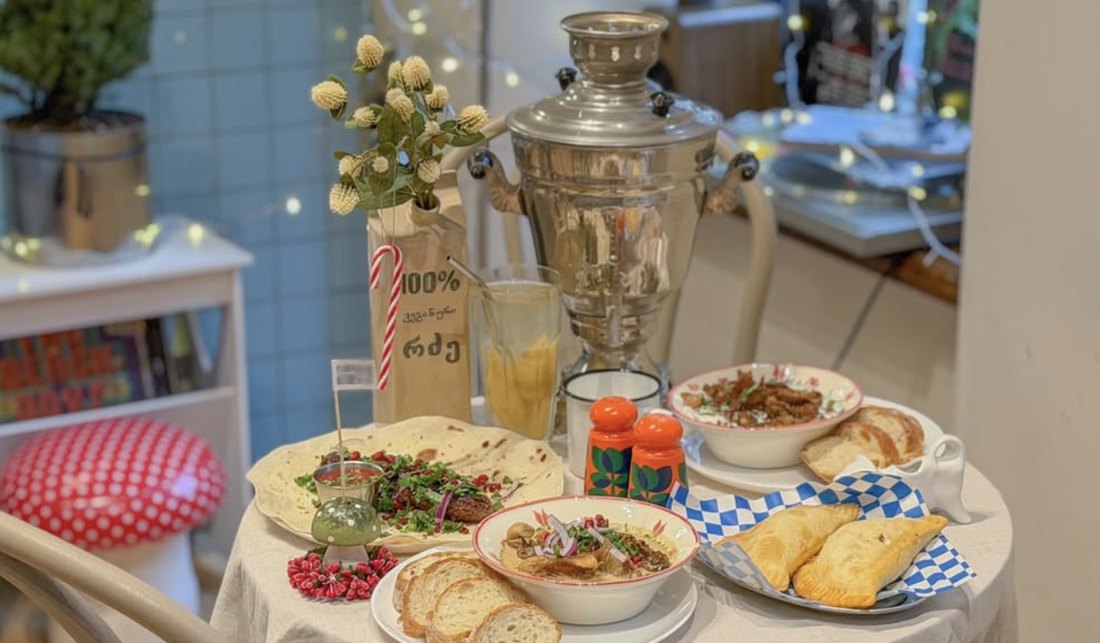 A table spread with chebureki, salad, soup and a samovar