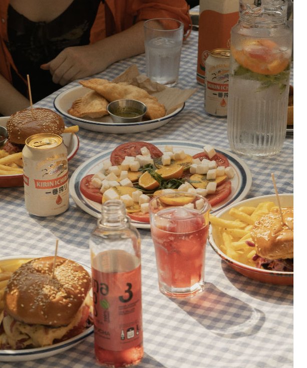 Burgers, tomato salad and drinks on a gingham tablecloth